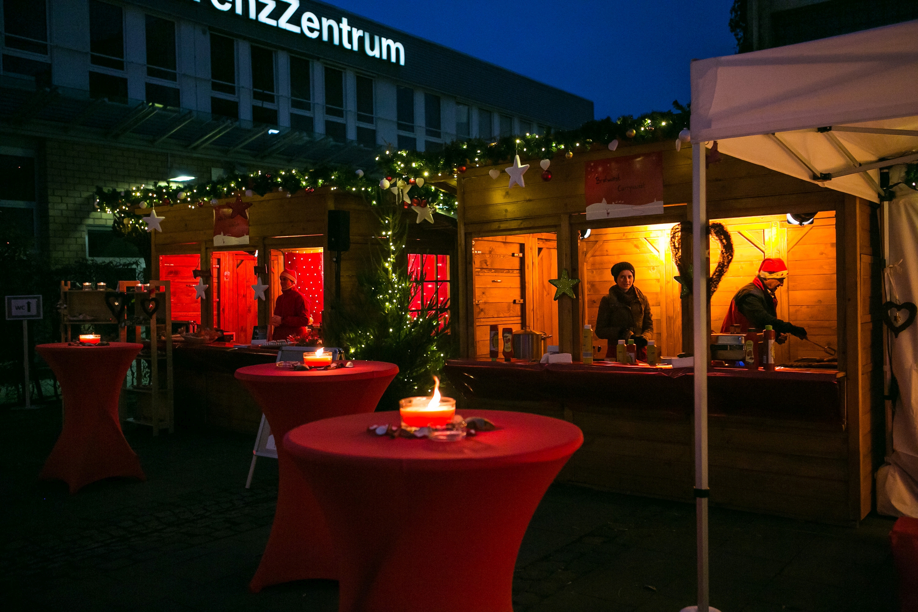 Weihnachtliche Marktstände mit Lichtern auf einem Firmengelände