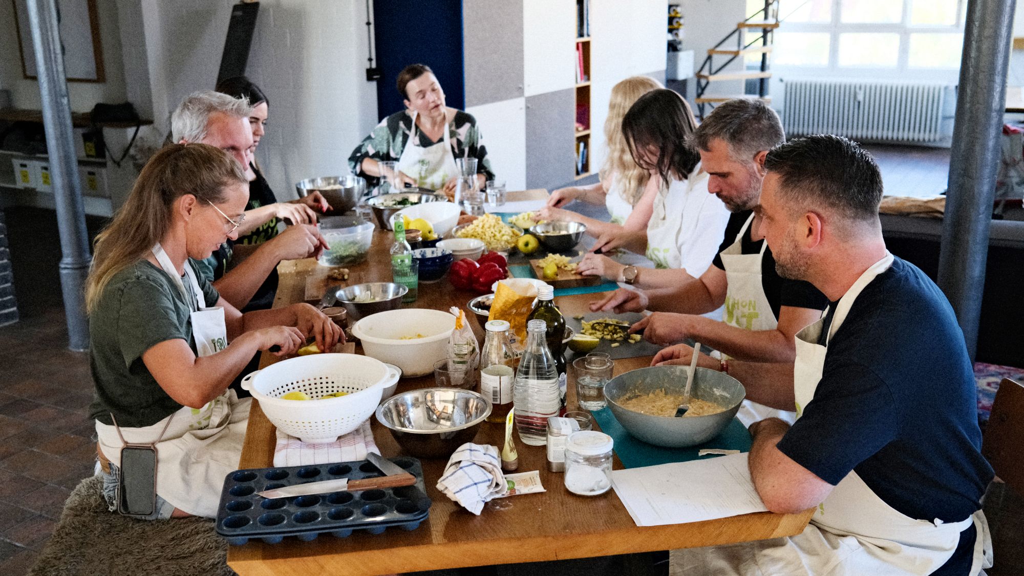 Team schneidet gemeinsam Zutaten am langen Tisch